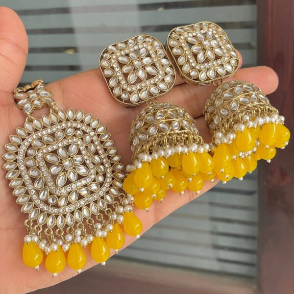 Beautiful yellow coloured earrings with large size tikka made of brass metal and gold plated with American pearls
