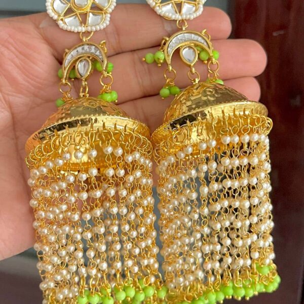 Dangling earrings made of olive green crab and white coloured beads and kundan. Whose base metal is alloy and is gold-coloured plated.