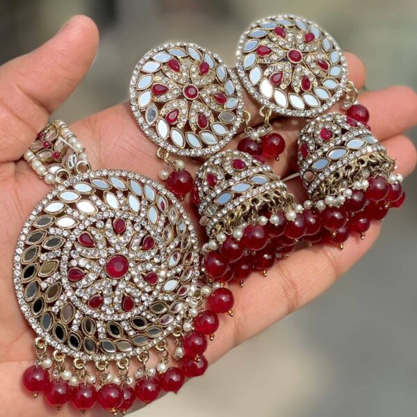 Mirror Jhumka with artificial maroon pearls and beautiful tikka which is made of gold-plated alloy and is projected on the palm