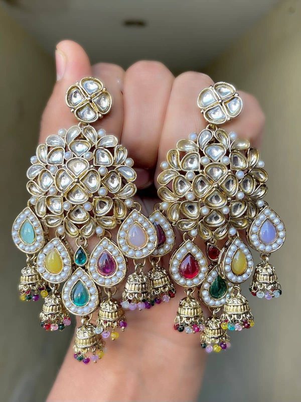 Beautiful Kundan and multicolour pearl earrings are made of alloy and have gold colour plated on them, which are presented and held in the hands.
